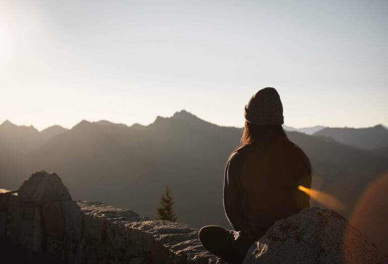 Girl sitting down meditating looking at the sunrise